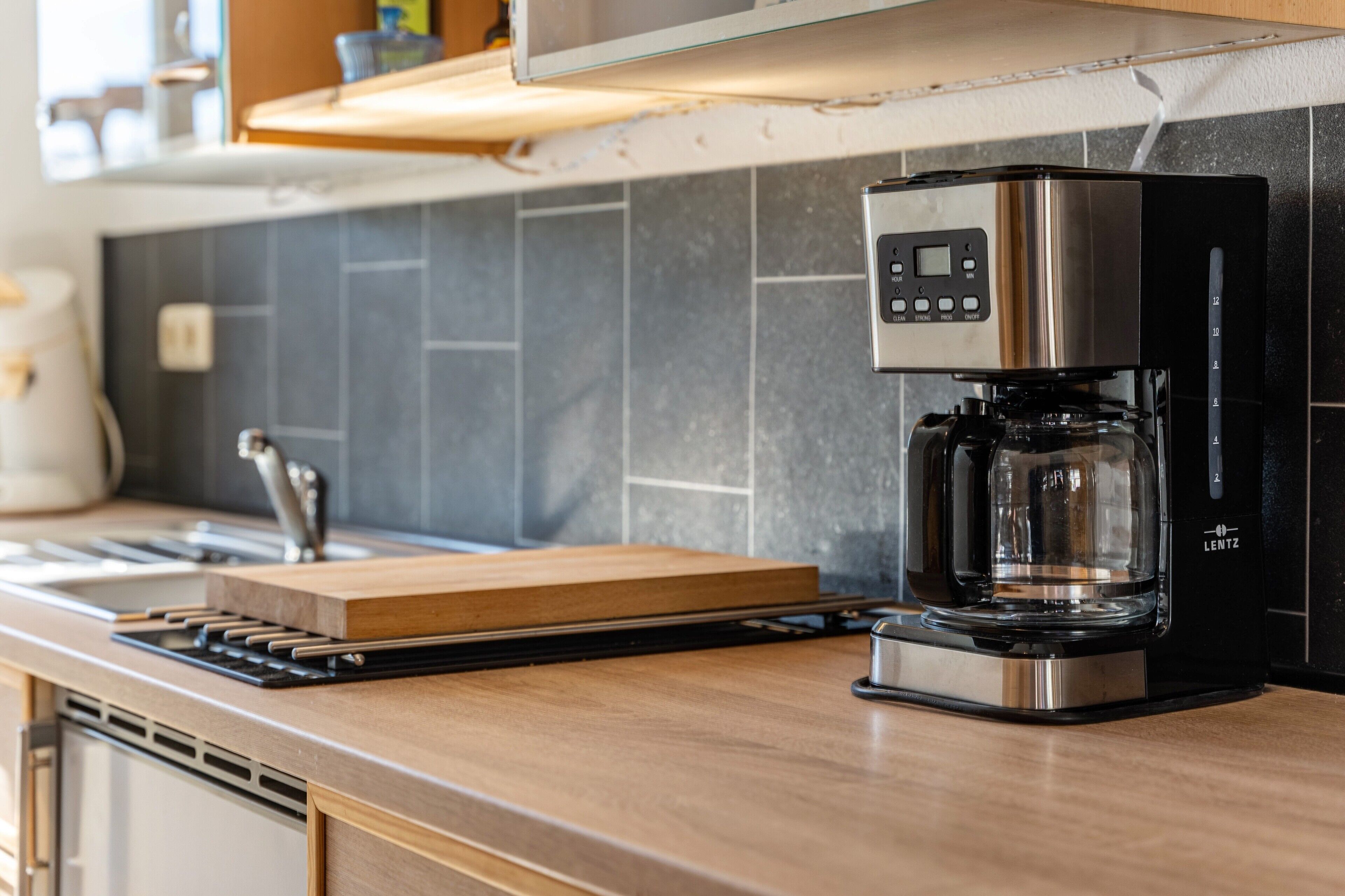 Eine moderne Küche mit Kaffeemaschine, Schneidebrett aus Holz und Spüle aus Edelstahl.