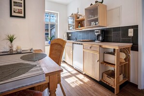 Une cuisine compacte dotée de meubles en bois, d’une machine à café et d’un coin repas avec une table et des chaises.