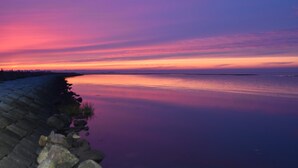 Un rivage paisible au coucher du soleil, avec une digue en pierre.