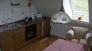Une cuisine compacte équipée d’un évier, d’une cuisinière et d’un coin repas avec une nappe à carreaux.