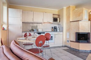 A compact kitchen with a dining area, a built-in microwave, a coffee maker, and a fireplace. - Apartment 'Habichtssicht' with Lake View, Shared Terrace and Wi-Fi (Buschvitz)