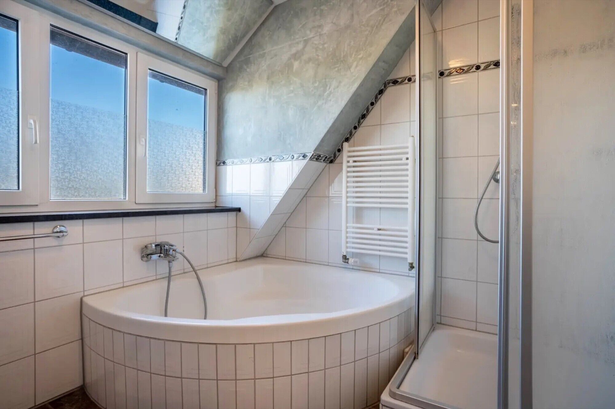 A bathroom with a bathtub, shower, and a window.