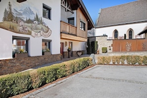 A building with a mural, a balcony, and a stone wall.