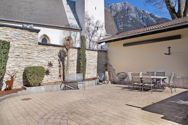 A patio with outdoor furniture, stone walls, and a mountain backdrop.