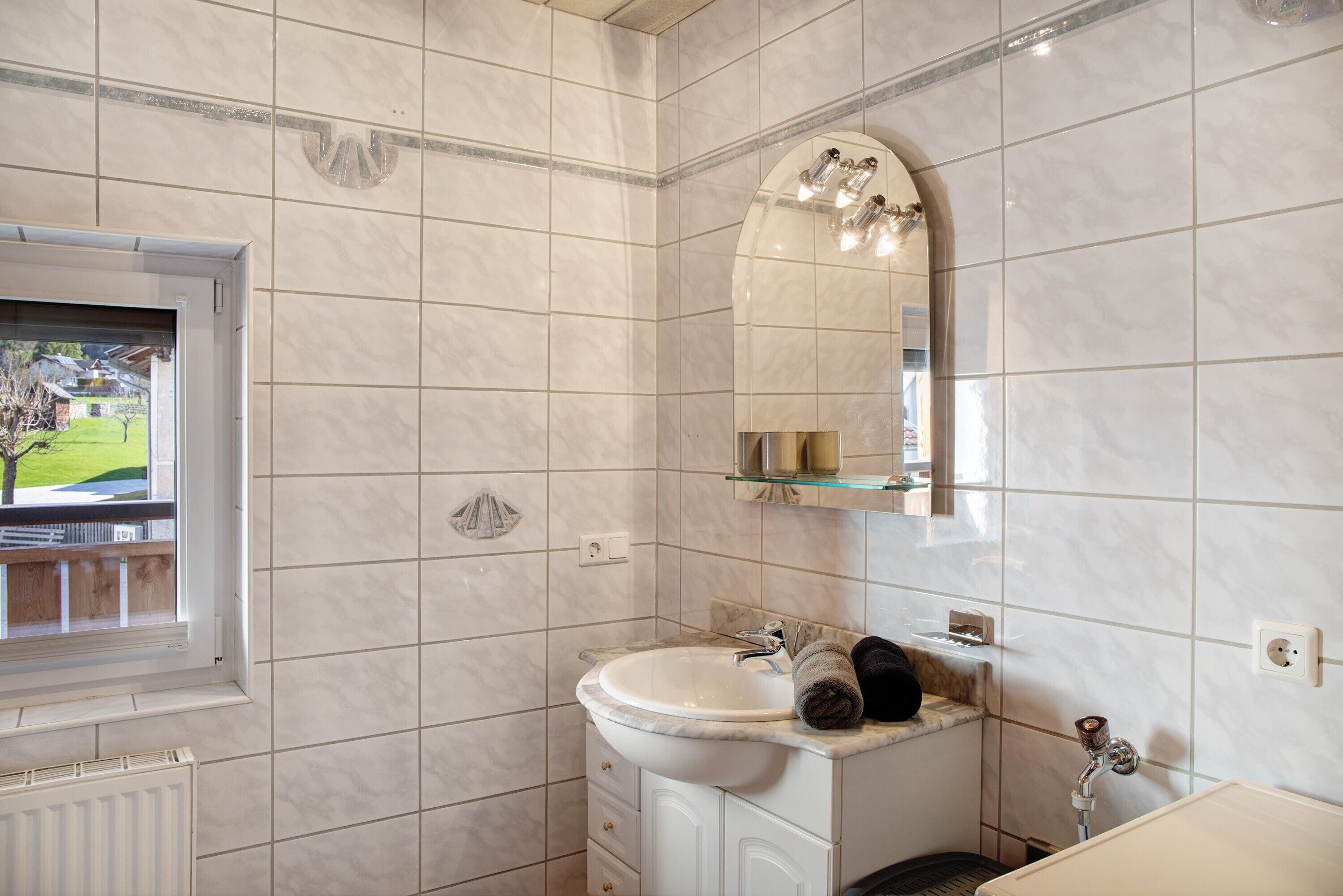 A bathroom with a sink, mirror, and window.
