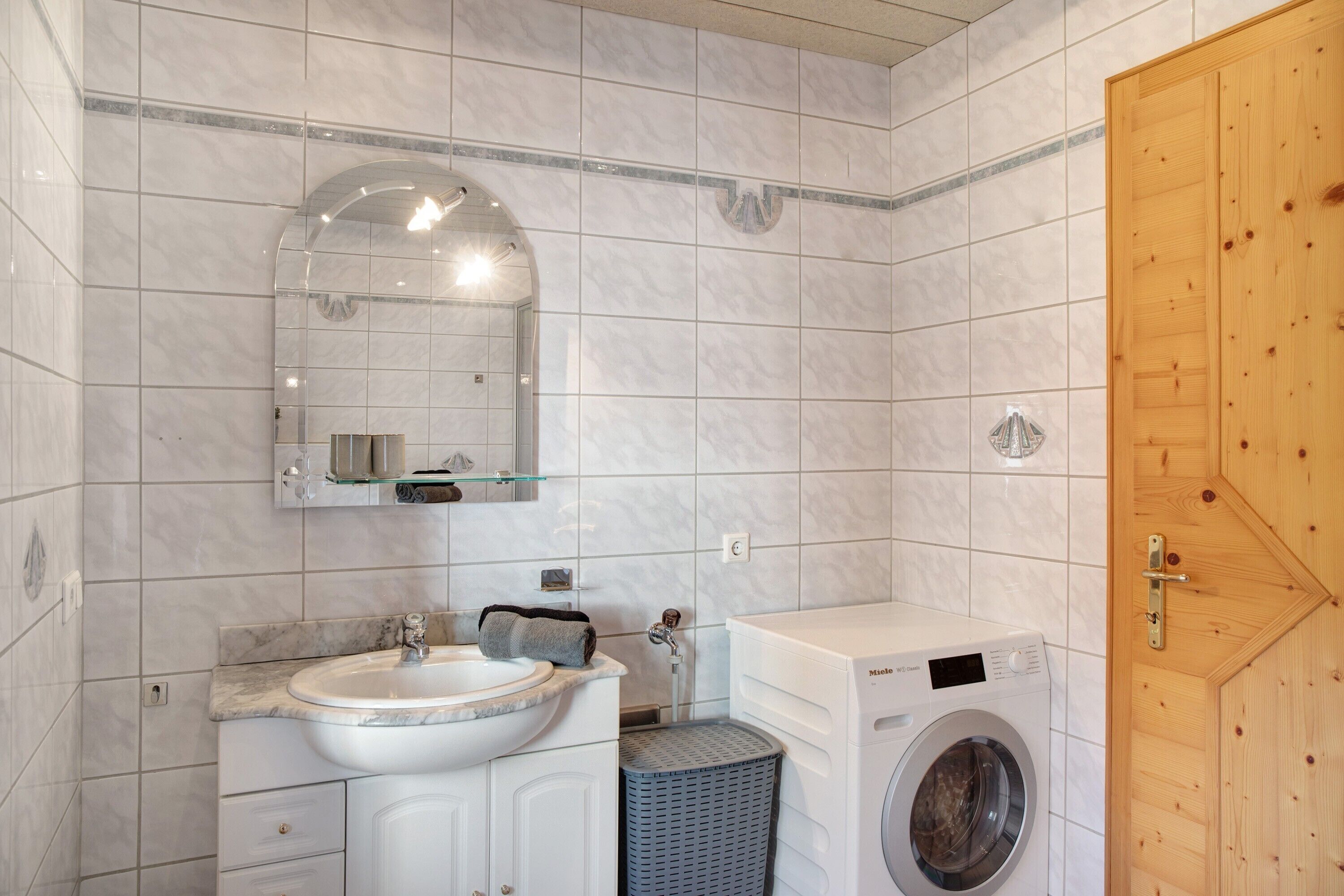 A bathroom with a sink, mirror, and washing machine.