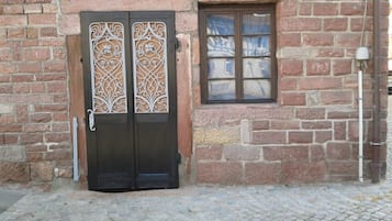 Ein Backsteinhaus mit doppeltürigem Eingang, verziert mit aufwendender Metallverzierung, und einem kleinen Fenster mit Gittermuster.