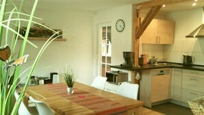 Eine kleine Küche mit Holzausstattung, einer Kaffeemaschine und einer Uhr an der Wand.
