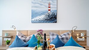 Une chambre d’hôtel avec un lit, une table de chevet sur laquelle se trouvent une bouteille, un verre et un bol de fruits.