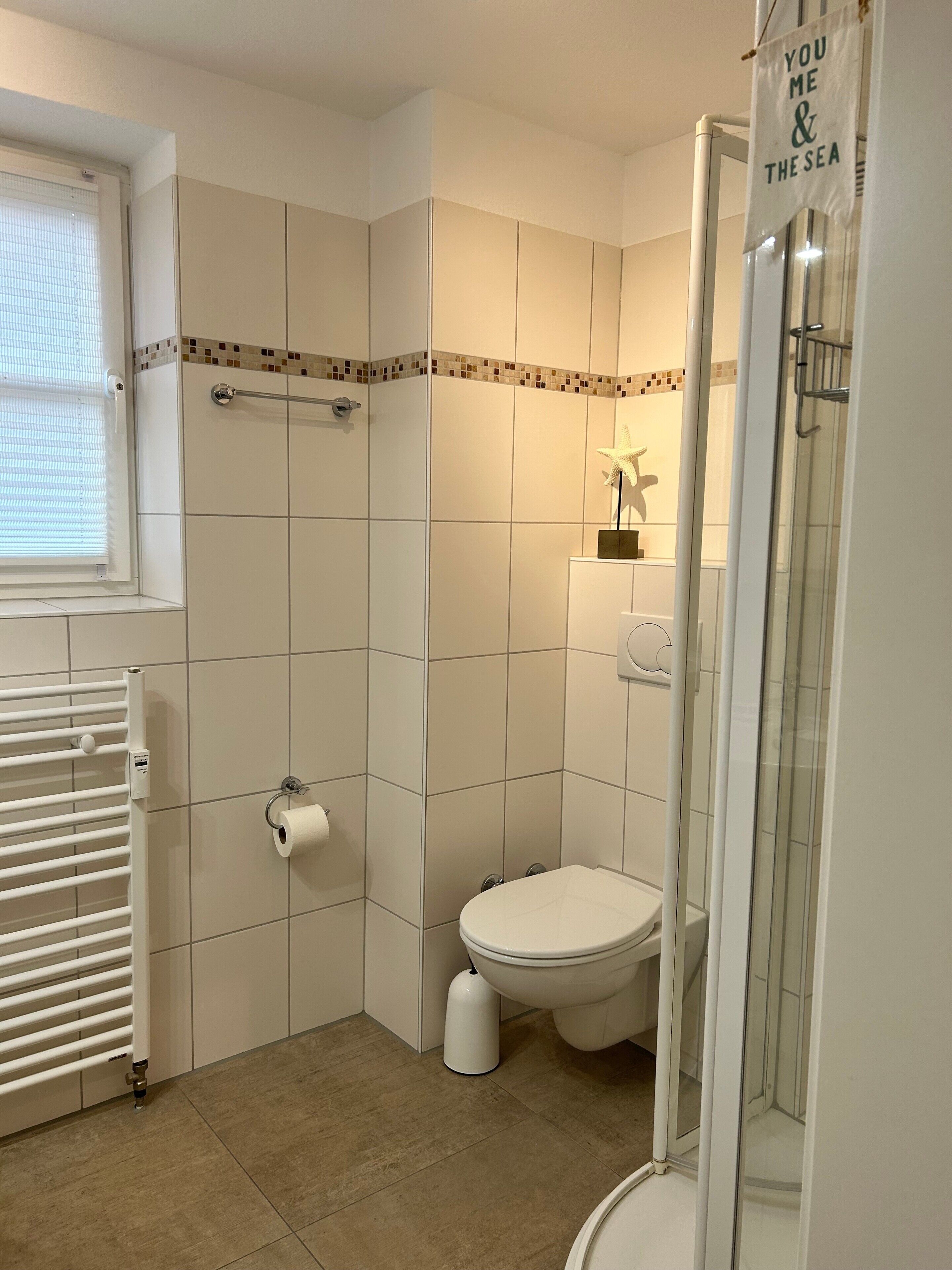 A bathroom with a toilet, a shower, and a towel rack.
