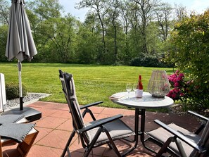 Eine Terrasse im Freien mit Tisch, Stühlen, einer Weinflasche und einem Buch.