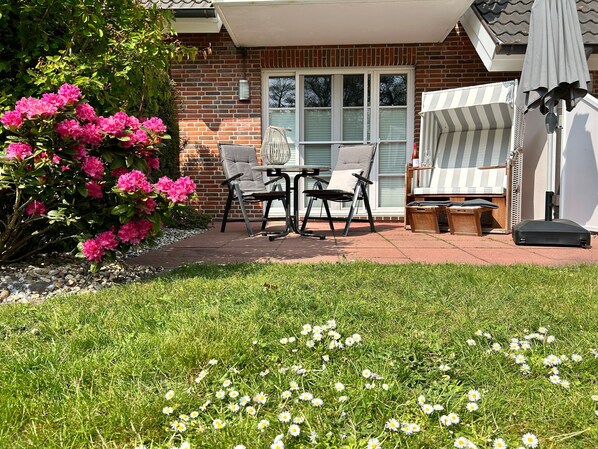 Eine Terrasse mit Gartenmöbeln, einer Backsteinmauer und einem Blumenbeet.