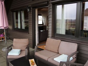 Un espace patio aménagé avec des meubles en osier, une table et un barbecue.