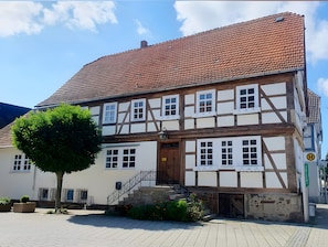 A traditional half-timbered building with a tiled roof, a staircase, and a small garden area.