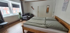 Une chambre à coucher avec un lit, une chaise, une plante en pot et une fenêtre.