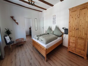 Un dormitorio con una cama de madera, un armario, un escritorio y una silla.