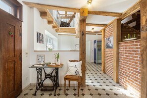Una habitación con techo de madera, pared de ladrillo, una mesa con un jarrón y una silla con cojín.