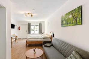 A modern, well-lit room with a bed, sofa, and a dining area.