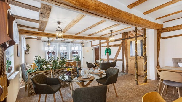 Un comedor con vigas de madera, una mesa de cristal y sillas.