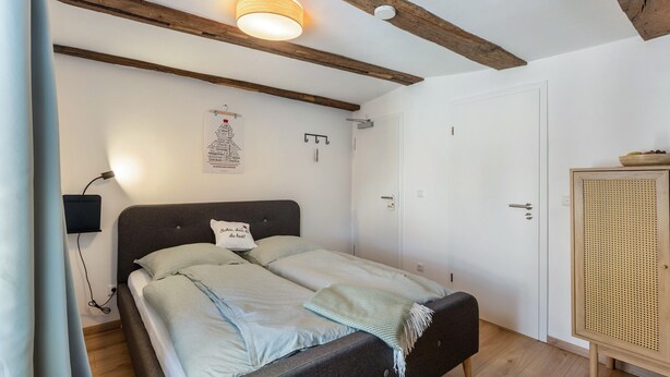 Un dormitorio con cama, lámpara de noche, armario e iluminación en el techo.