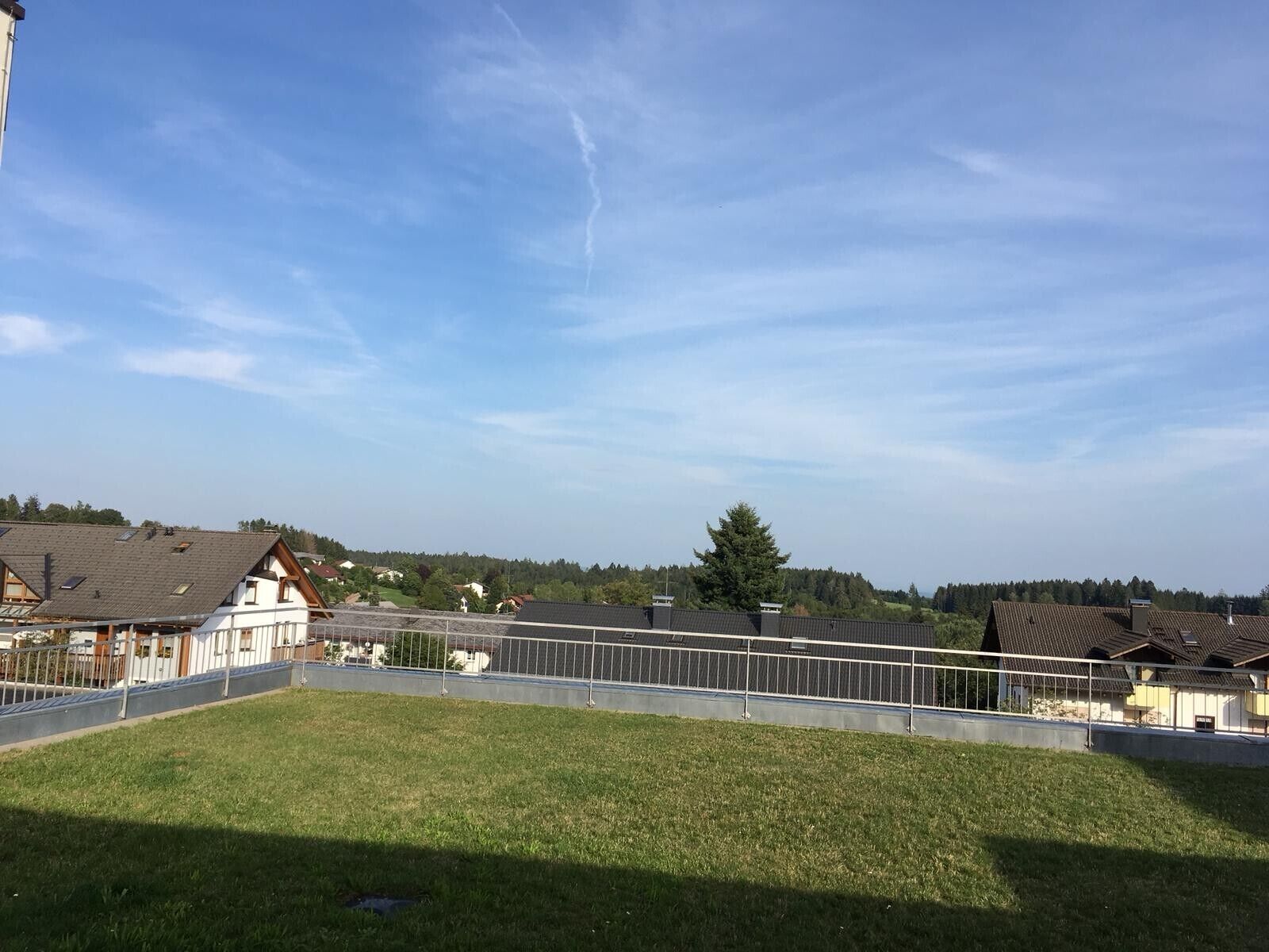 A residential area with houses, a fenced yard, and a clear sky.