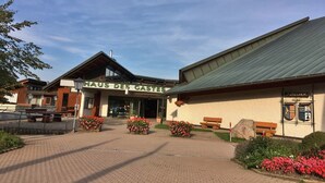 Rakennuksessa on kyltti, jossa lukee »HAUS DES GASTES», ja sen edessä on kivetty sisäänkäyntialue, jossa on penkkejä ja kukkapenkkejä.
