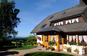 Une maison avec un toit en pente, de nombreuses fenêtres et un jardin bien entretenu.