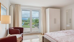 A bedroom with a bed, a sofa, a table, and a sliding glass door leading to a balcony. - Apartment 'Gartenblick' with Mountain View, Private Terrace and Wi-Fi (Sankt Peter)