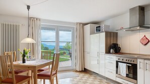 A kitchen with a view, a dining area with chairs, and a table with a vase. - Apartment 'Gartenblick' with Mountain View, Private Terrace and Wi-Fi (Sankt Peter)