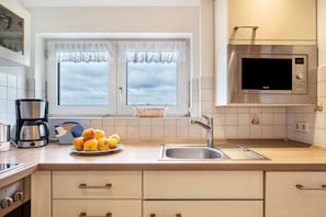 A modern kitchen with a stainless steel microwave, a coffee maker, and a fruit bowl on the counter. - Apartment 'Abendrot, 55qm' with Mountain View, Shared Terrace and Wi-Fi (Sankt Peter)