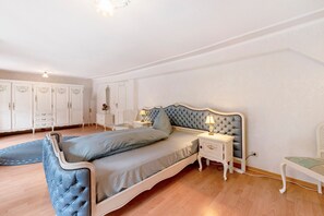 Ett sovrum med en säng, sängbord, ett litet bord, en stol och en garderob.