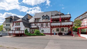 A traditional half-timbered building with a balcony, a covered entrance, and a paved driveway. - Holiday Home 'Moseljuwel' with Sauna, Pool & Large Moselle Terrace (Traben-Trarbach)