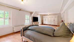 A bedroom with a bed, a dresser, a television, and a window with curtains. - Holiday Home 'Moseljuwel' with Sauna, Pool & Large Moselle Terrace (Traben-Trarbach)