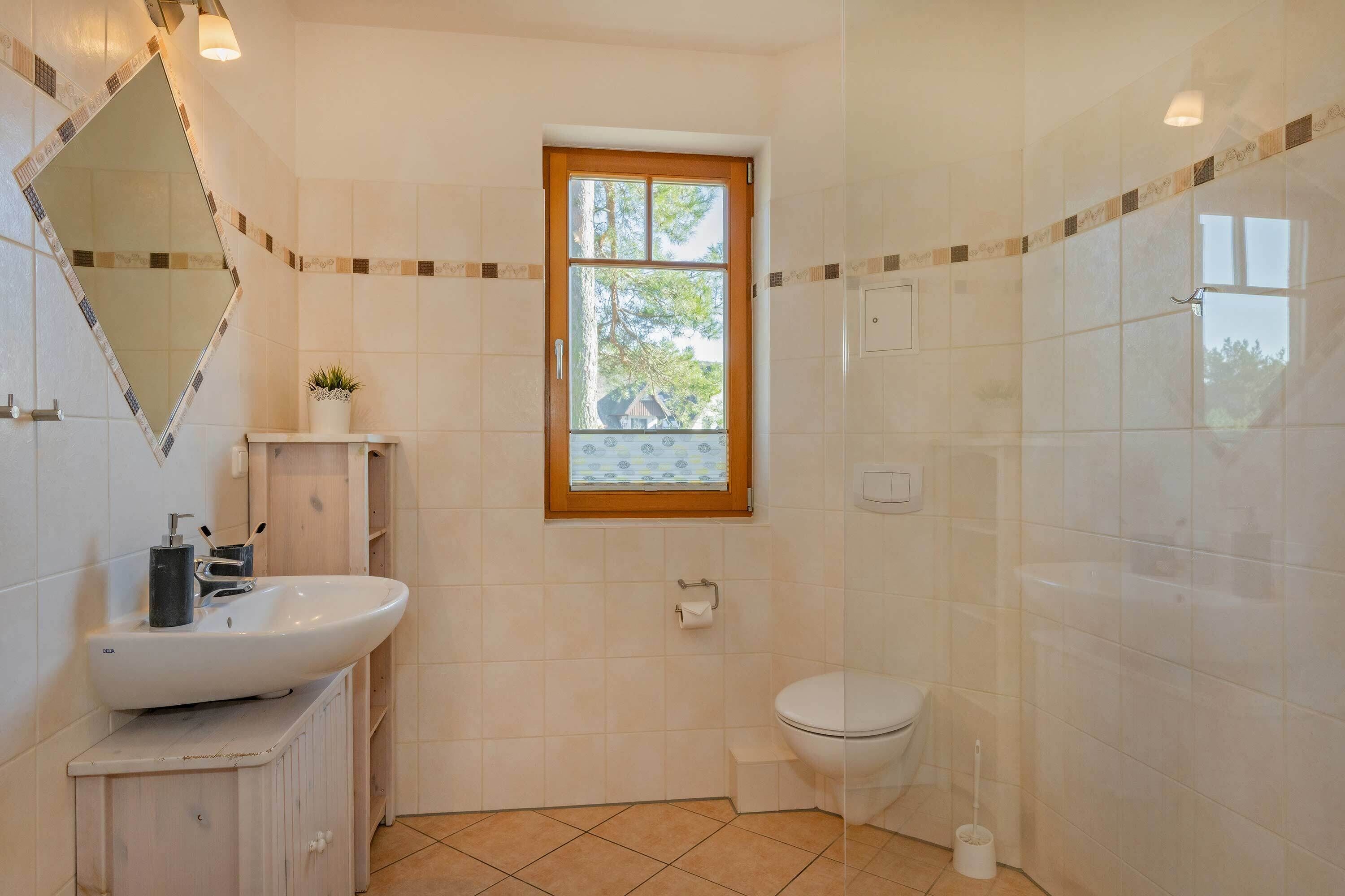 Et badeværelse med håndvask, toilet og vindue.