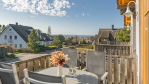 A terrace with a table, chairs, and a flower arrangement. - Modern vacation apartment with garden, sauna & whirlpool - ideal for families (Loddin)
