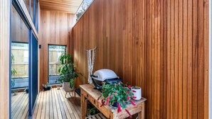 A wooden interior with a wooden floor, a table with a grill, and potted plants.