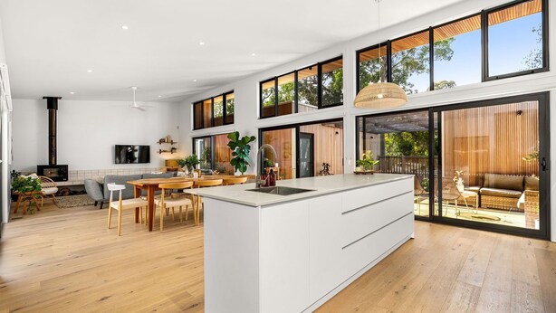 A spacious kitchen with a large island, wooden flooring, and a dining area with a view of the outdoors.