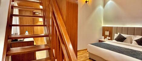 A wooden staircase leading to a bedroom with a bed and a nightstand.
