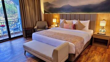 Habitación de hotel con una cama grande, una silla, un escritorio y vistas al exterior.