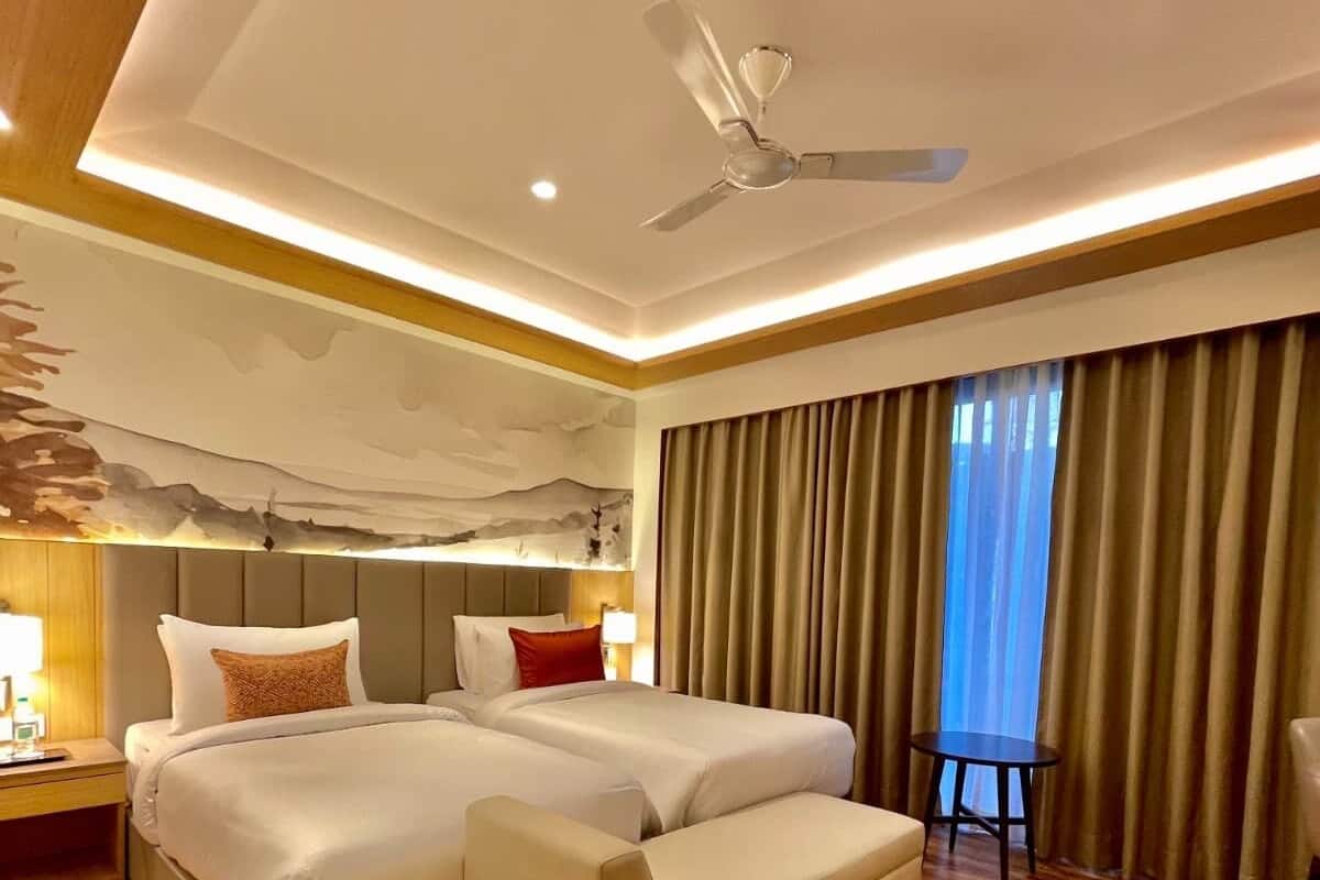 Ein Hotelzimmer mit einem großen Bett, einer Schlafcouch, einem Deckenventilator und Holzboden.