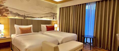 A hotel room with a large bed, a sofa, a ceiling fan, and a view of the outdoors through the window.