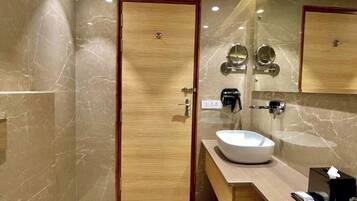 A modern bathroom with a marble floor, a wooden door, a large mirror, a sink, and a vanity with a towel rack.