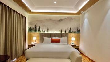 Une chambre d’hôtel comprenant un lit, un canapé, un ventilateur de plafond, une table de chevet avec une lampe et une fresque murale.