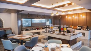 Une cuisine moderne dotée d’un îlot central, d’un coin repas avec tables et chaises, et d’un bar pour prendre le petit-déjeuner.