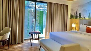 Une chambre d’hôtel avec un lit, un canapé, une chaise, une petite table et un ventilateur de plafond.