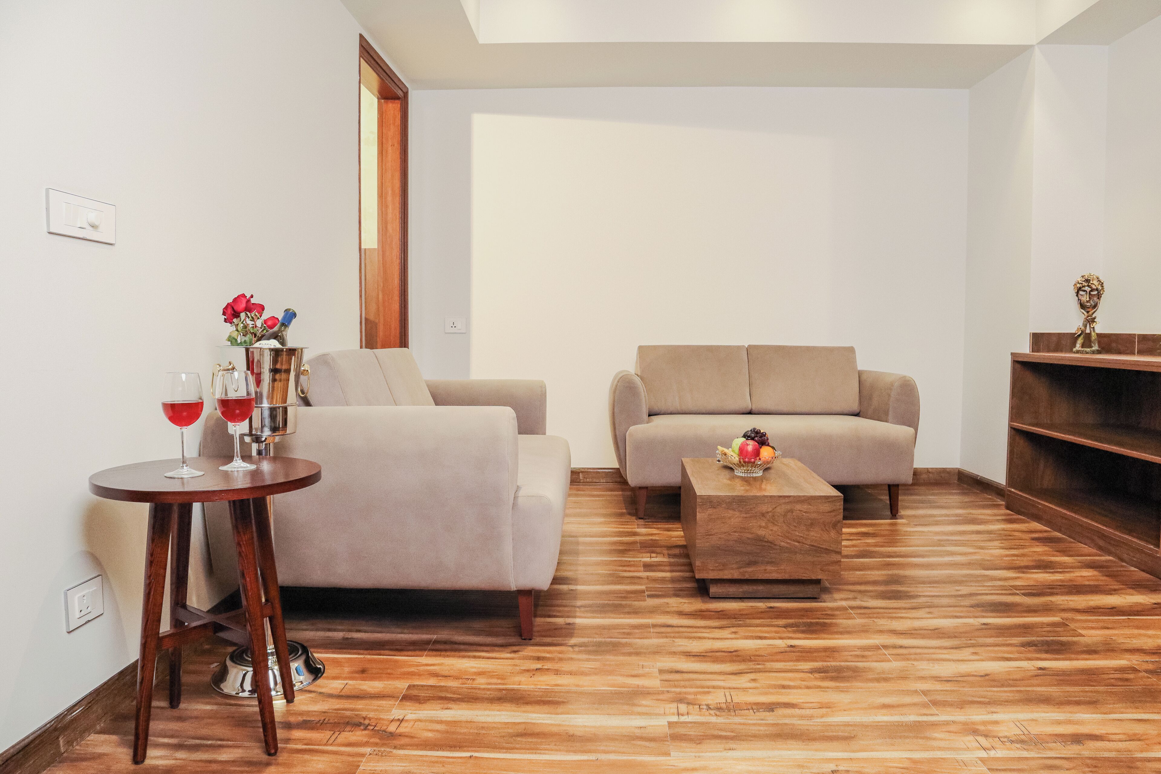 Una sala de estar con un sofá, una mesa de centro y una mesita auxiliar con una copa de vino y flores.