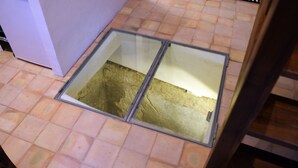 Een kamer met een betegelde vloer en een raam met metalen kader.