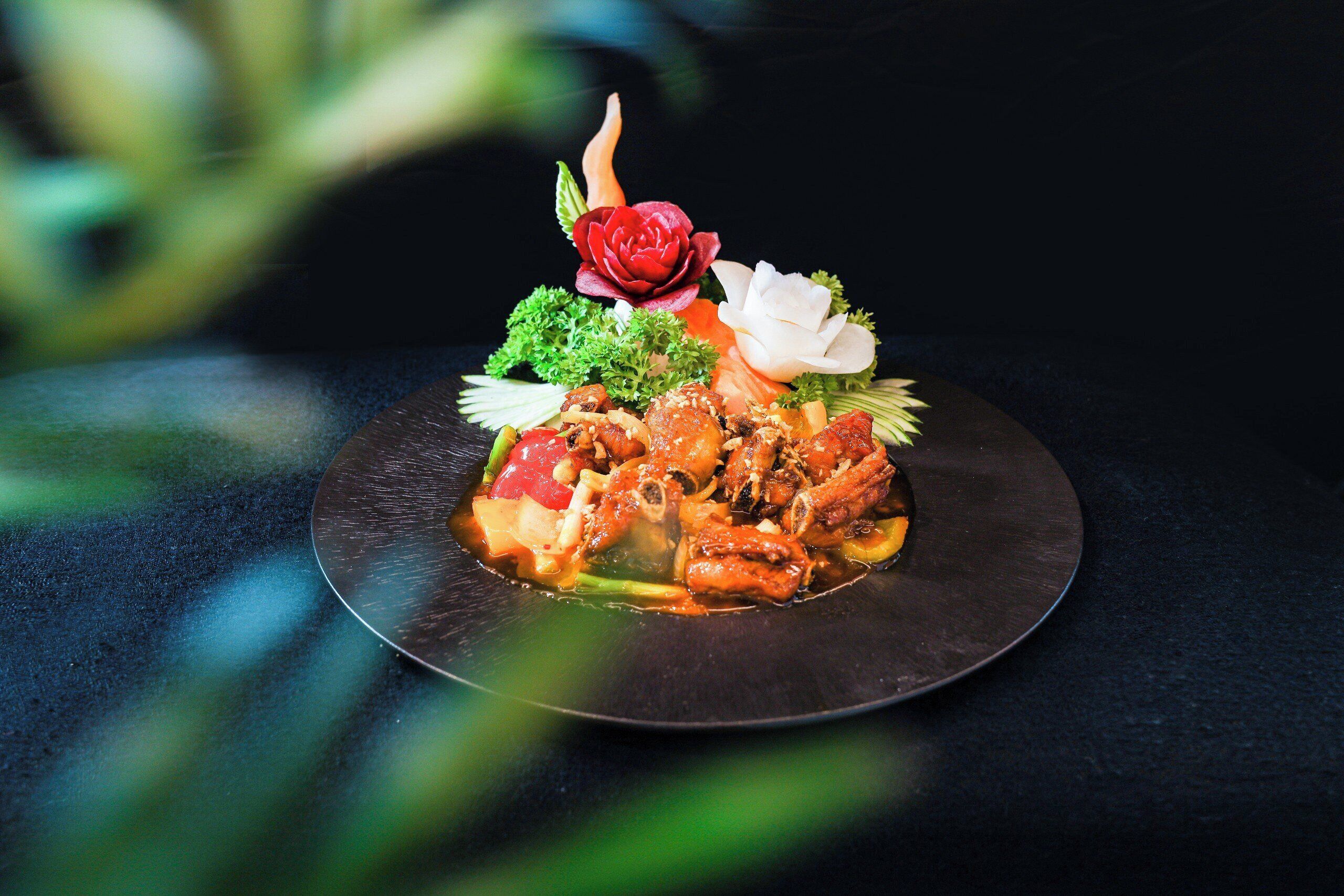 A plate of food with a decorative arrangement of vegetables and a rose.
