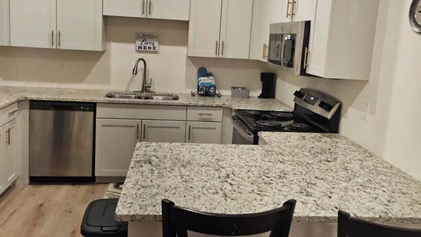 A modern kitchen with white cabinets, stainless steel appliances, and a granite countertop. - Madison Cozy House for Comfort and Relaxation (Madison)