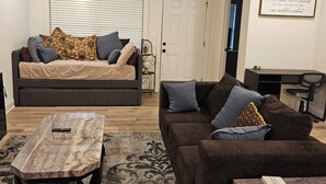 A living room with a sofa, a coffee table, and a TV. There is a door and a wall with a framed quote. - Madison Cozy House for Comfort and Relaxation (Madison)